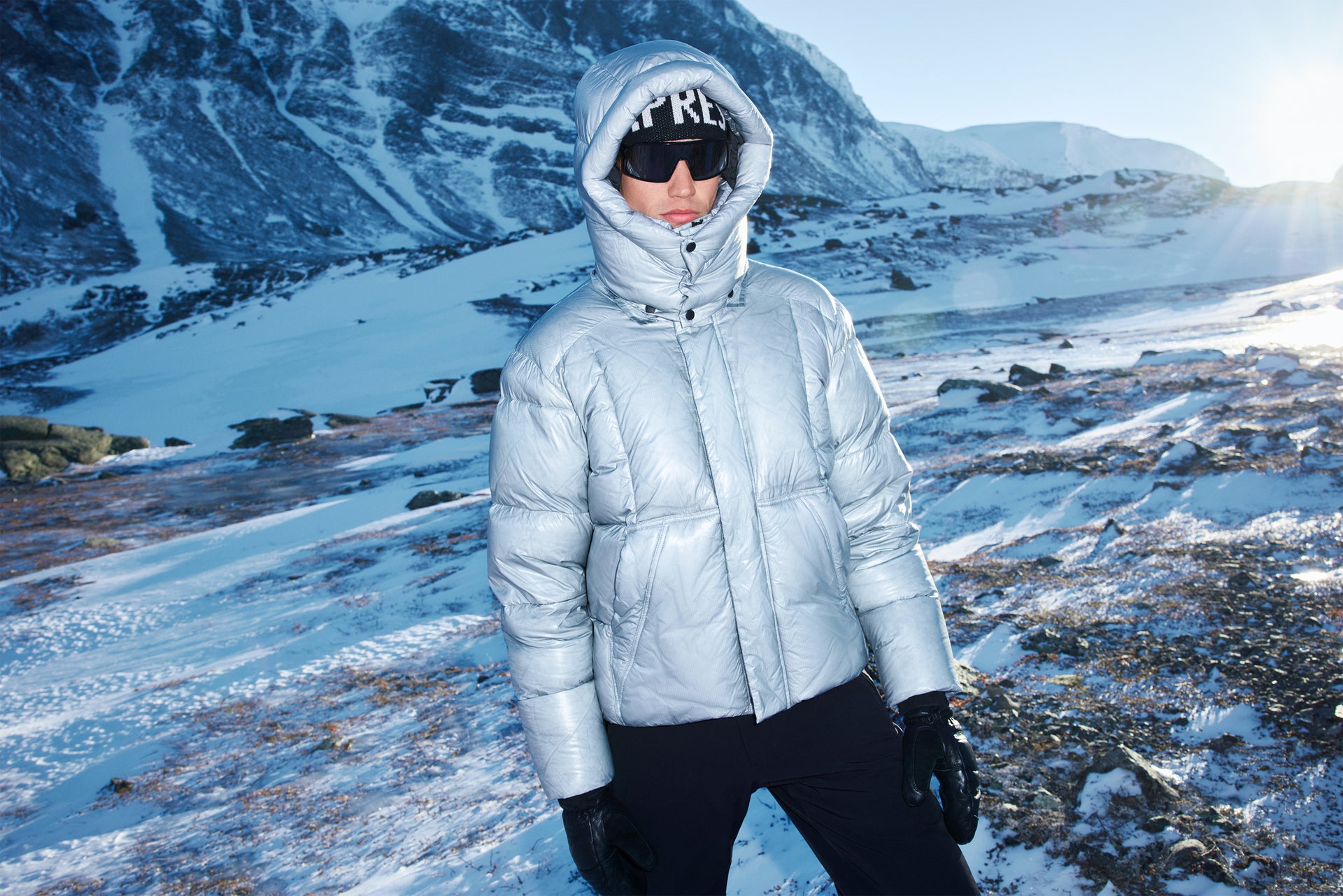 Person wearing a light gray puffer jacket in a snowy mountain landscape