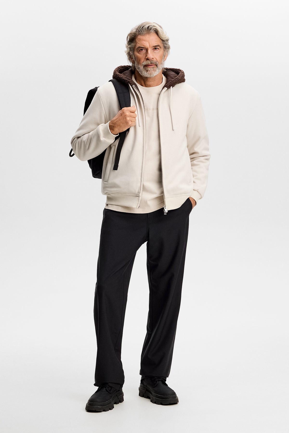 Model wearing the Henry Bonded Hoodie in Moonbeam with front zip and hood in a studio setting.