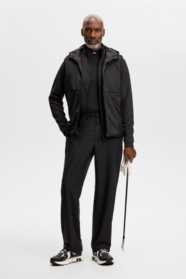 Model wearing the black M Solarcore 3 in 1 Jacket, holding a golf club in a studio setting.