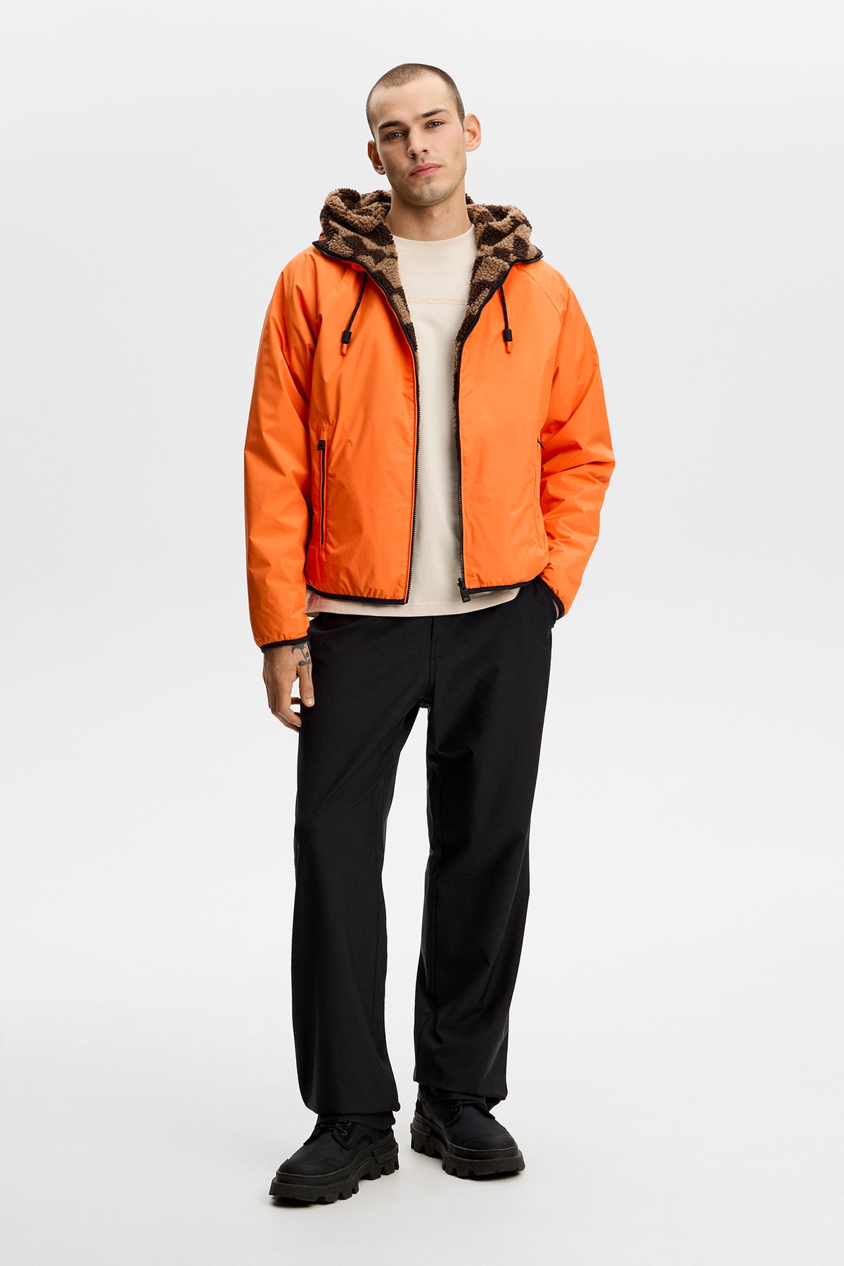 Model wearing the Rory Reversible Teddy Jacket in Golden Poppy with hood in a studio setting.