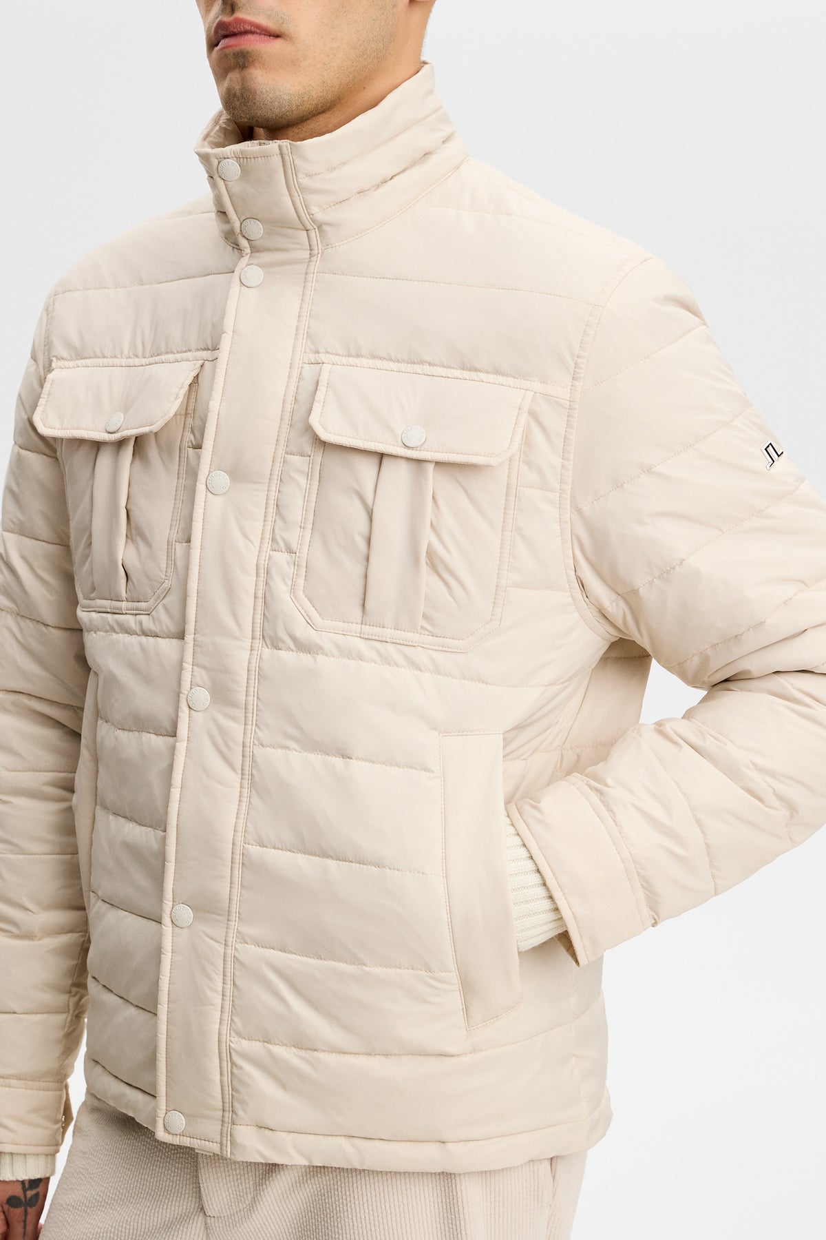 Close-up front view of the Bailey Light Padded Jacket in Moonbeam with chest flap pockets and stand collar.