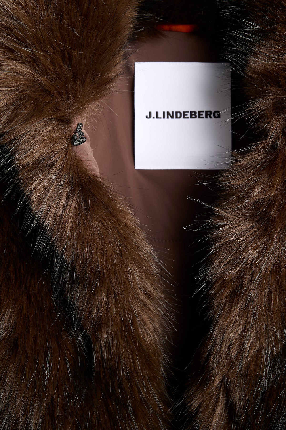 Close-up of the J.LINDEBERG inner label and Seal Brown faux fur on the Daria Faux Fur Ball Vest.