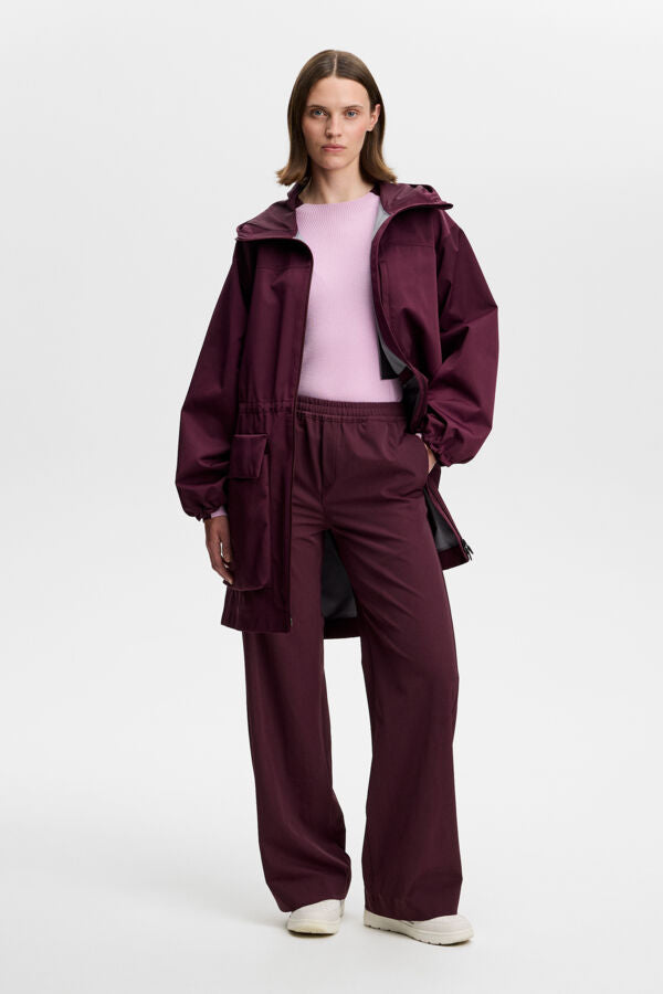 Front view: Model wearing the Anja Pant in Winetasting styled with a matching jacket.