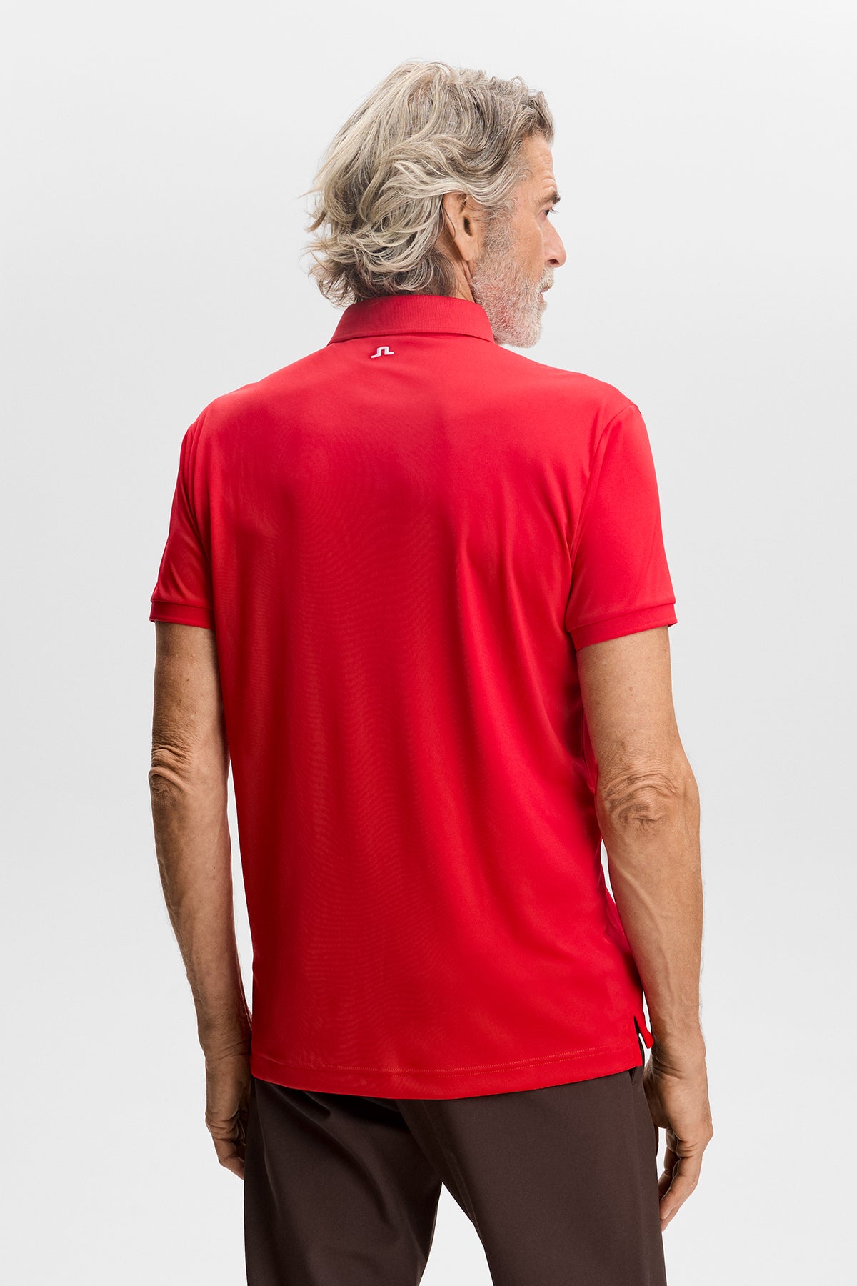 Tour Tech Polo in red, back view showing the embroidered Bridge logo below the collar.