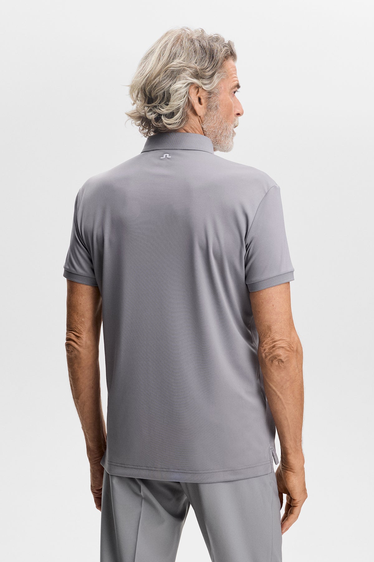 Back view: Tour Tech Polo in Night Owl gray with embroidered Bridge logo on the upper back.