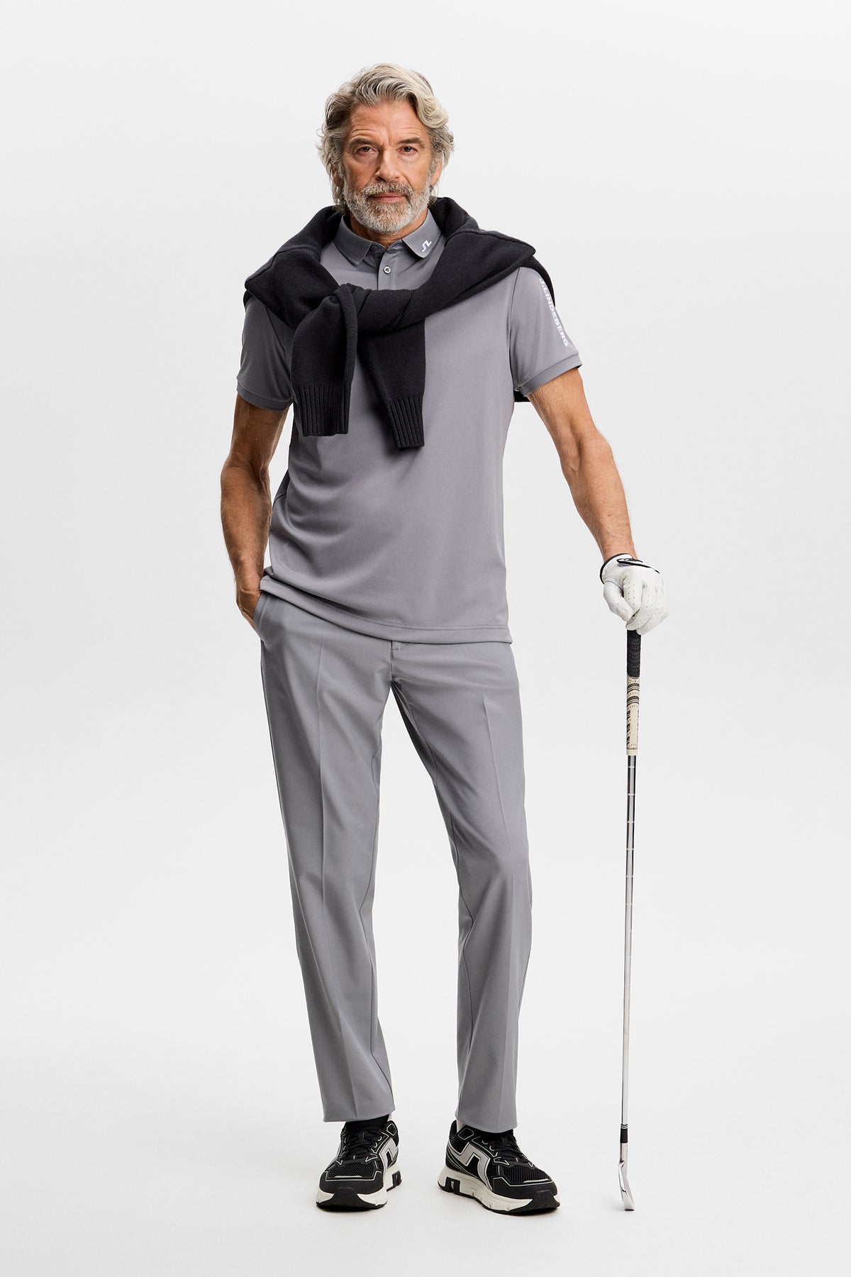 Model wearing the Tour Tech Polo in grey, styled with matching pants in a studio setting.