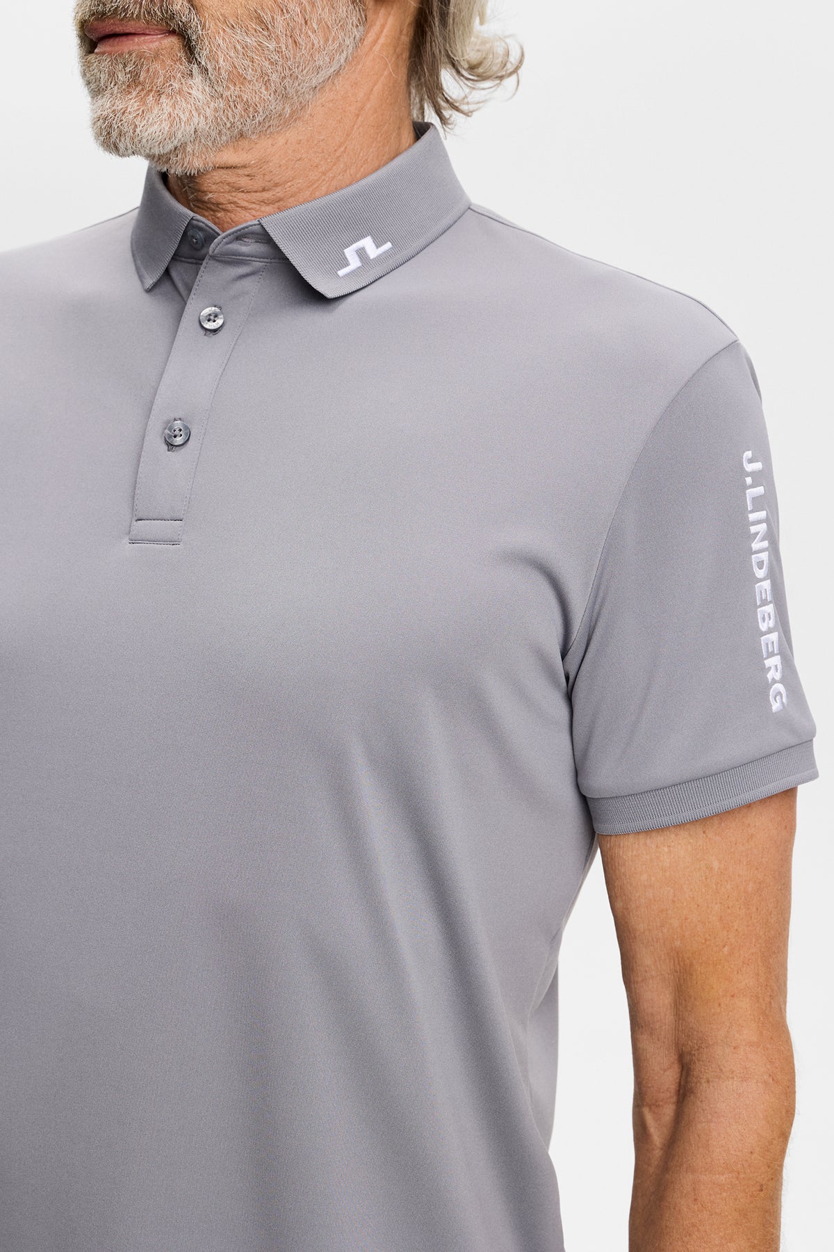 Close-up view of the Tour Tech Polo in gray, showing the embroidered Bridge logo on the collar and sleeve.