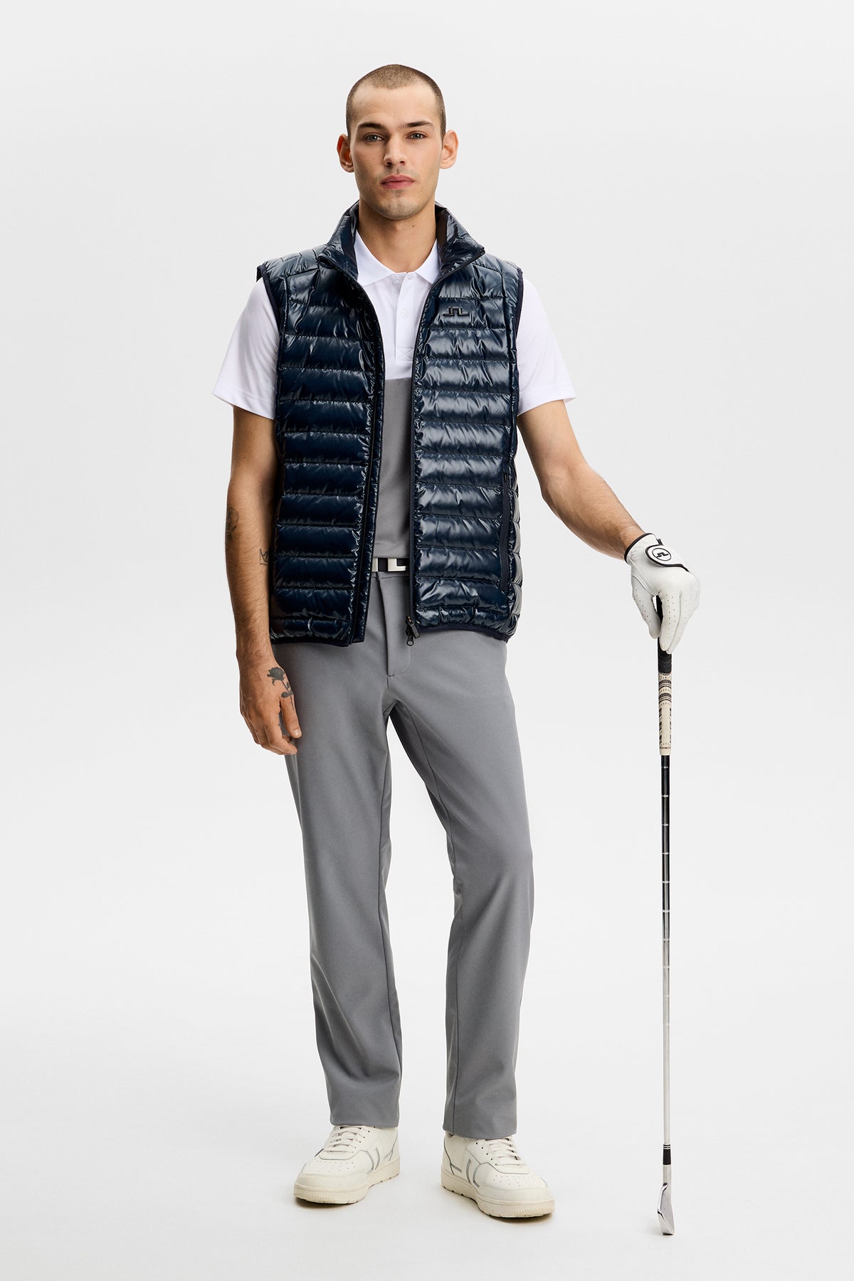 Model wearing the Mitch Bonded Players Pant in gray, styled with a vest and golf club.