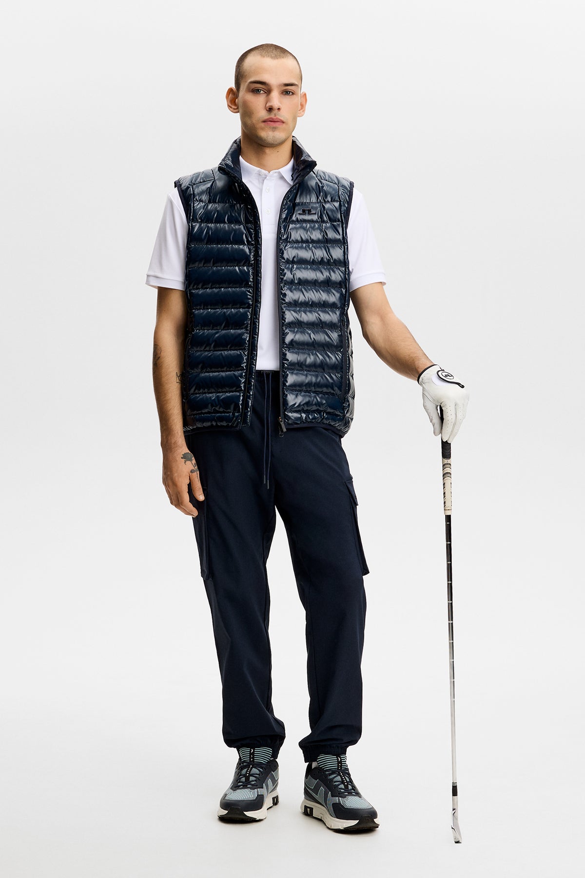 Model wearing the Harris Tech Pant in JL Navy with cargo pockets, holding a golf club.