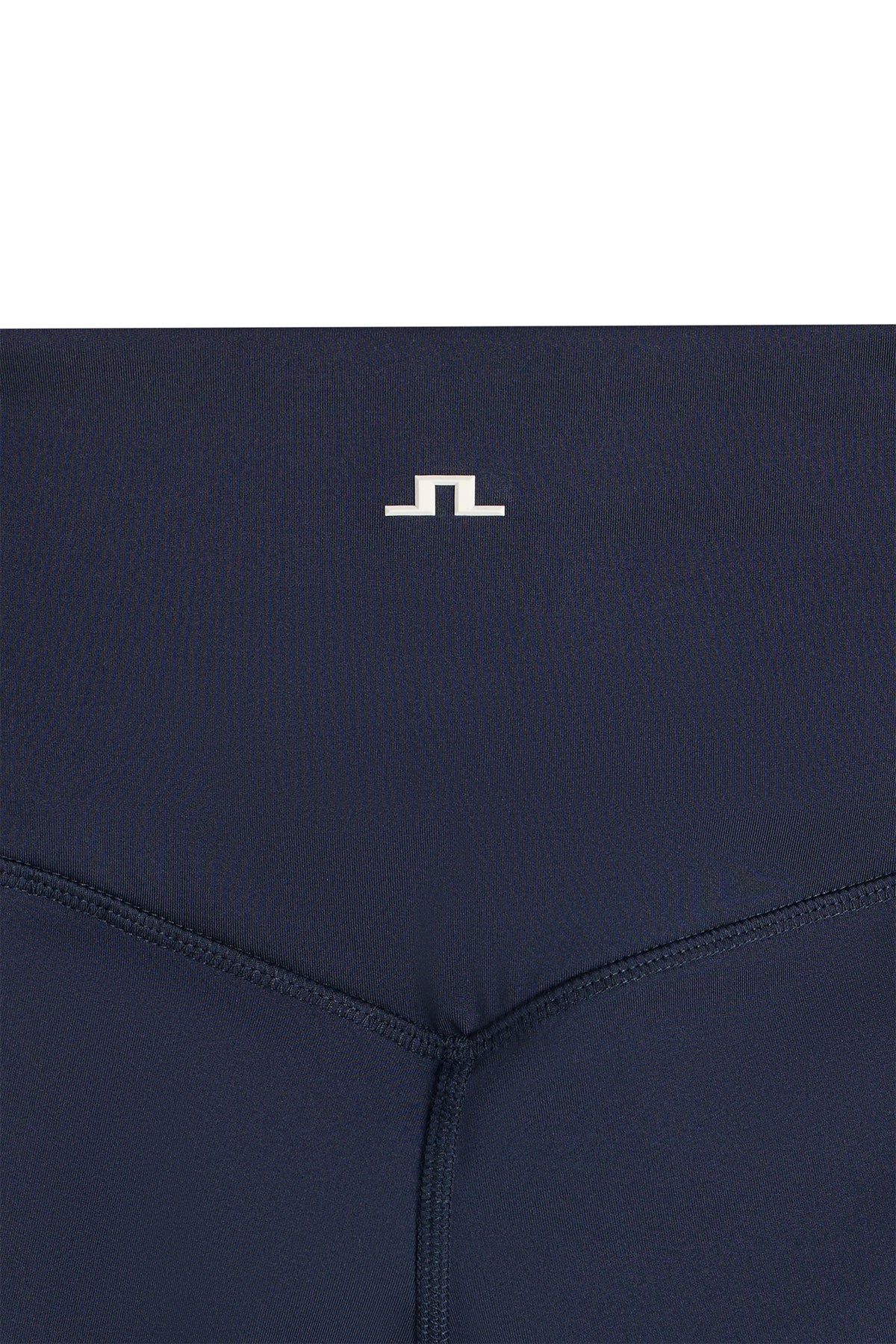 Close-up: Zienna Flared Leggings in JL Navy with white Bridge logo and flatlock seams.